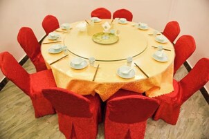 Una mesa redonda con mantel amarillo, rodeada de sillas rojas.