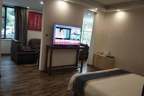 A hotel room with a bed, a TV on a stand, a chair, and a desk. - Jinggangshan Oriental Red Hotel (Jinggangshan City)