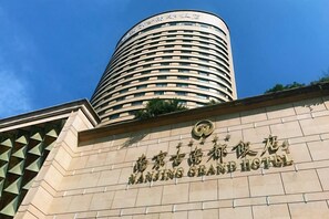 Nanjing Grand Hotels facade med en markant cylindrisk bygning og et skilt, der angiver hotellets navn.