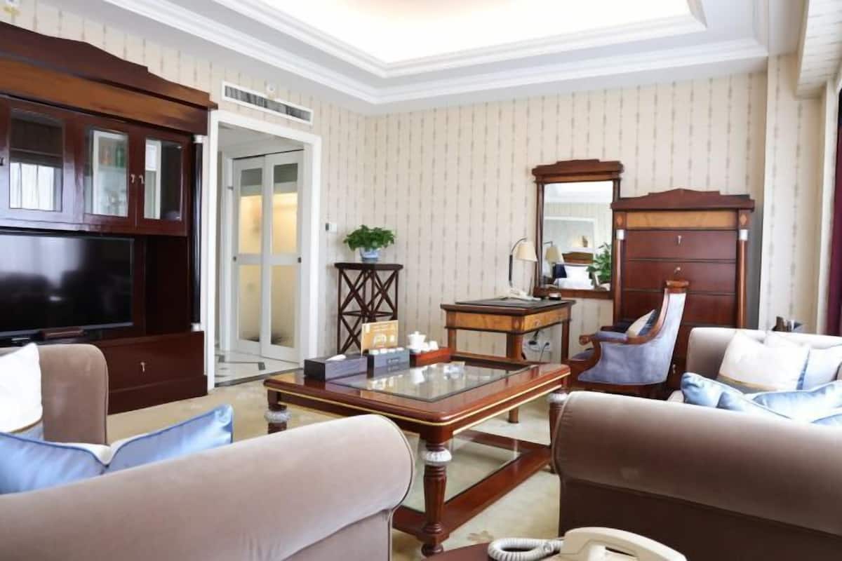 A living room with a television, wooden furniture, a glass coffee table, and a sofa.
