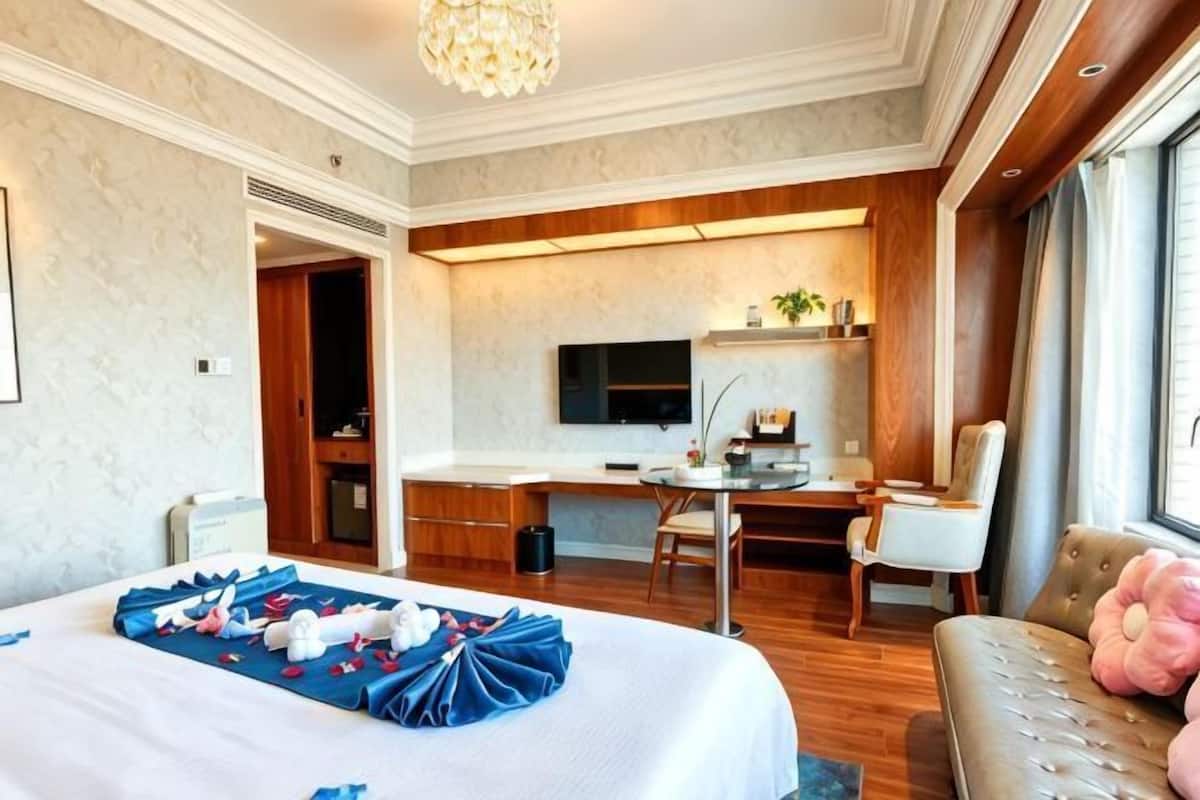 A hotel room with a bed, a desk, a TV, and a sofa.