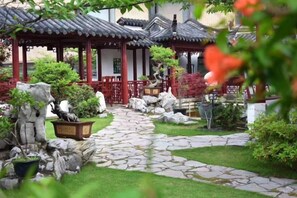 Een traditionele Japanse tuin met steenpaden, potplanten en een houten paviljoen.