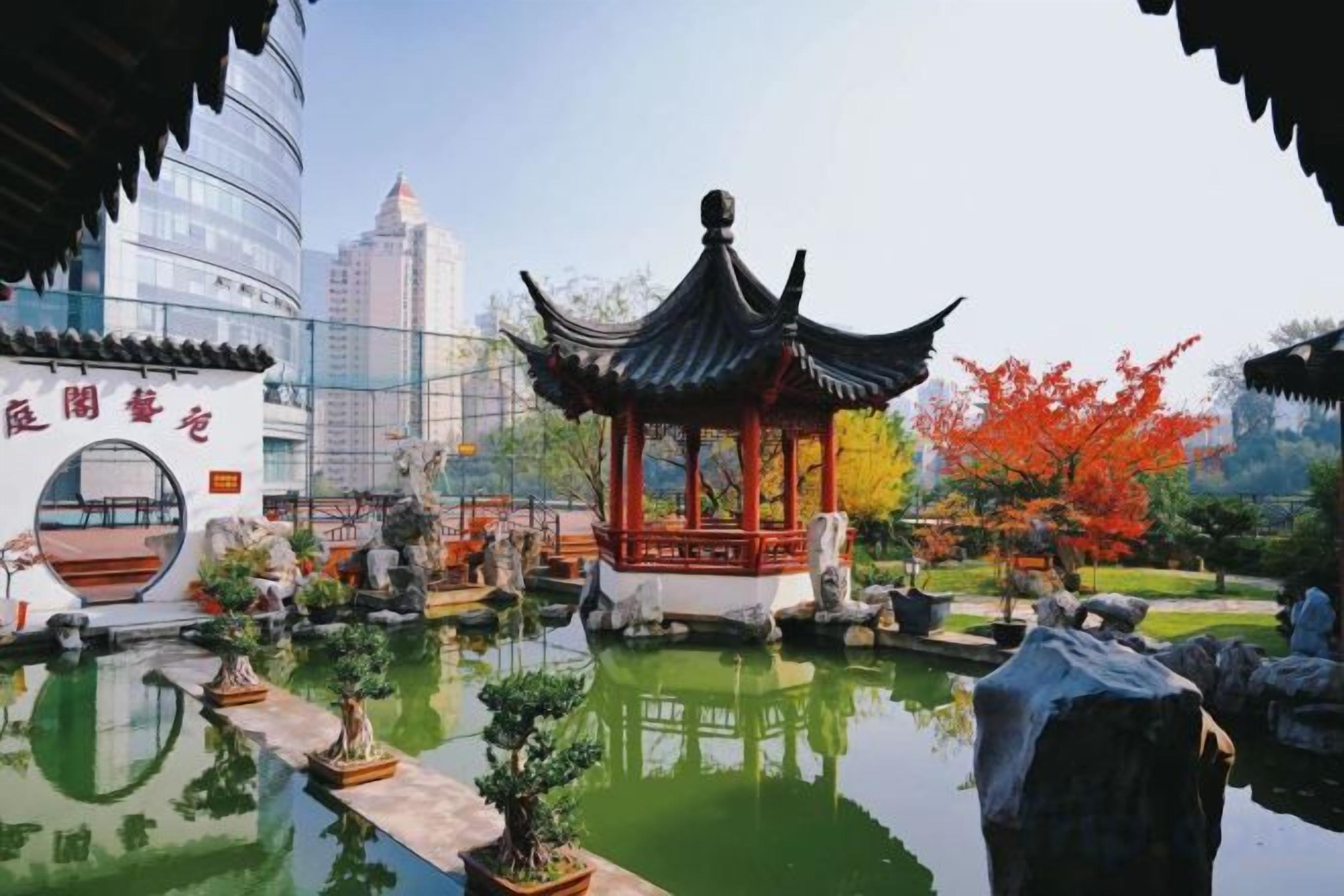 A traditional pavilion with a tiled roof, surrounded by a water feature and potted plants.