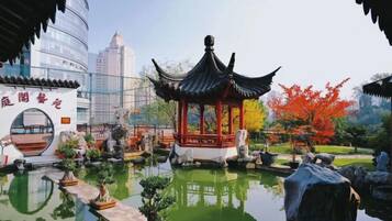 A traditional pavilion with a tiled roof, surrounded by a water feature and potted plants.