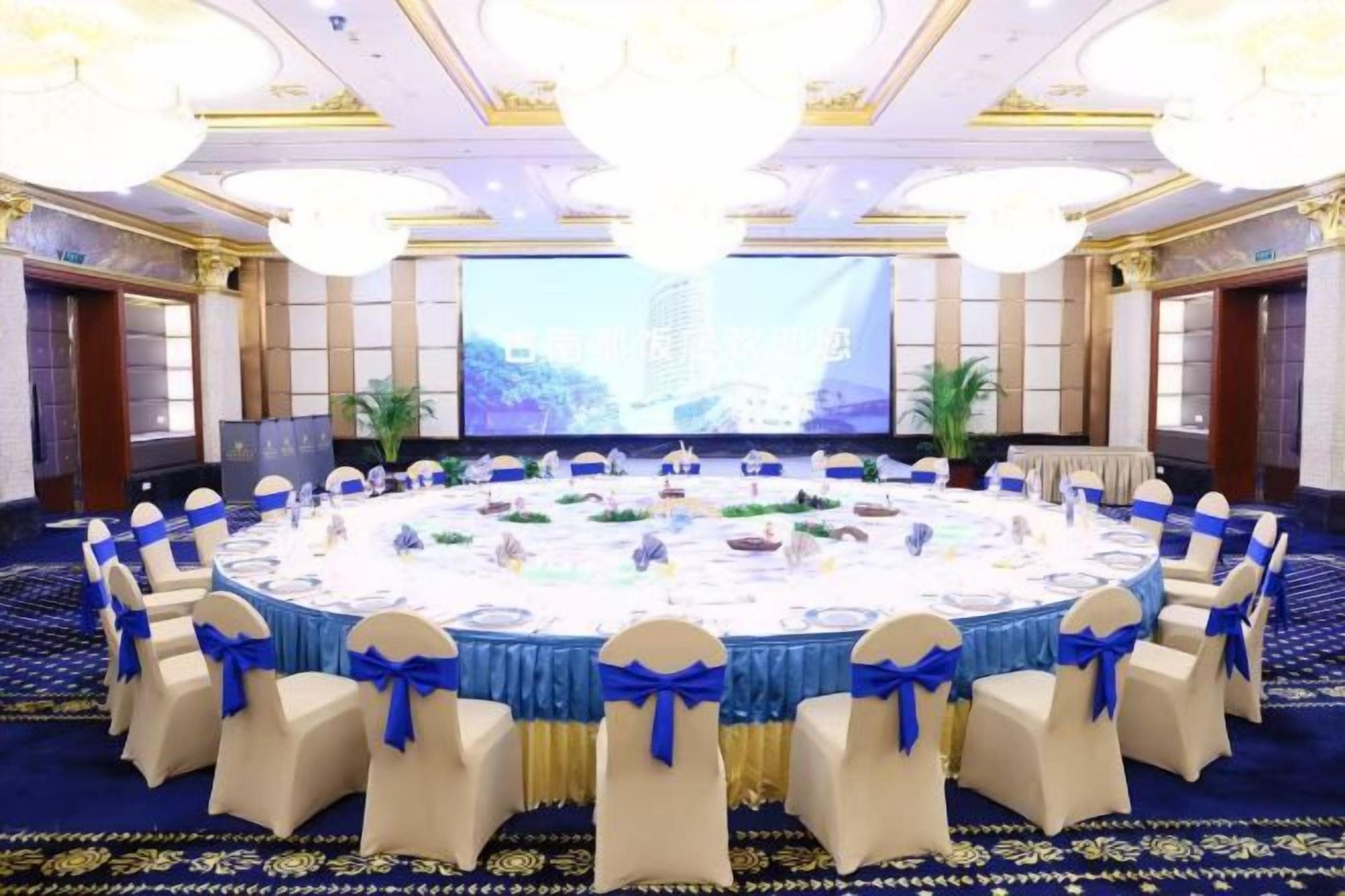 A conference room with a round table, chairs, and a large screen.