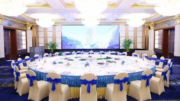 A conference room with a round table, chairs, and a large screen.