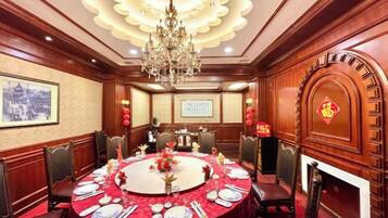 A conference room with a round table set for a meeting, surrounded by chairs, a chandelier, and traditional decor.