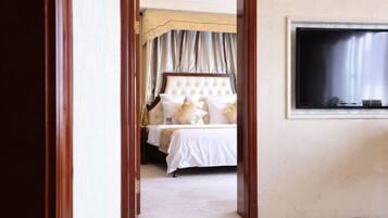 A hotel room with a bed, curtains, a television, and a wooden floor.