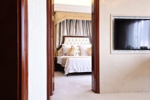 Habitación de hotel con cama, cortinas, televisor y suelo de madera.