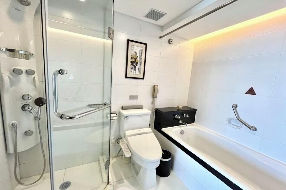 Een moderne badkamer met een douchecabine van glas, een toilet, een bad en een inlijsting foto aan de muur.