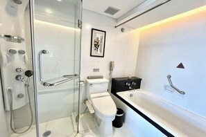 Een moderne badkamer met een douchecabine van glas, een toilet, een bad en een inlijsting foto aan de muur.