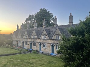 A row of traditional stone cottages with multiple chimneys, each with a small porch and a window. - Maple Cottage - Beautiful 2BD Home, Perfect For Family Retreat (Chipping Norton)