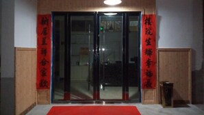 A hotel entrance with a red carpet, glass doors, and wooden paneling. - Loushanqiao Homestay No.2 (Shitai)