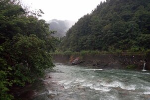 Un río que atraviesa un valle boscoso con una cascada a la derecha.