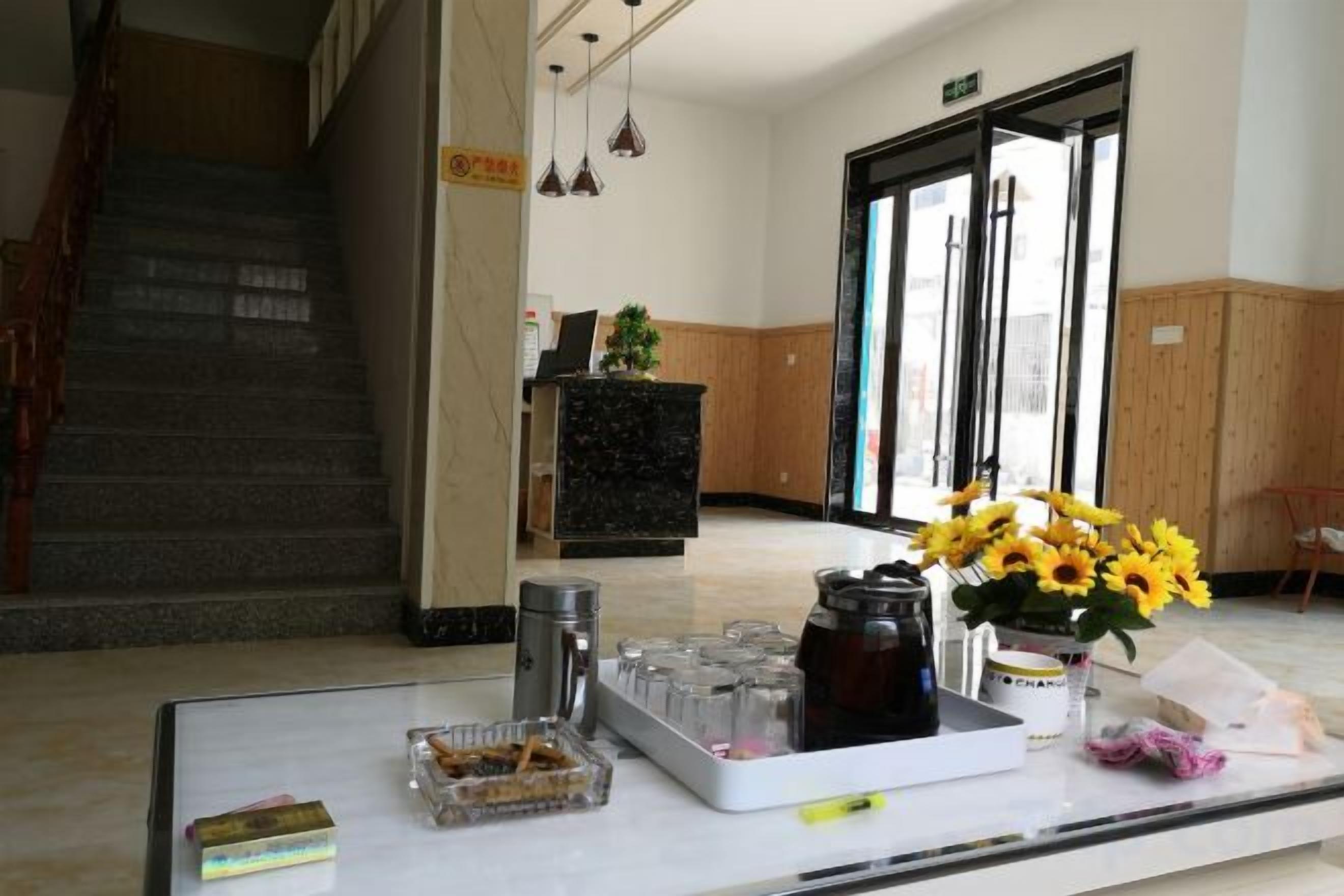 A reception desk with a vase of sunflowers, a tray with items, and a staircase in the background.