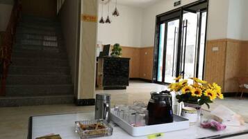 A reception desk with a vase of sunflowers, a tray with items, and a staircase in the background.