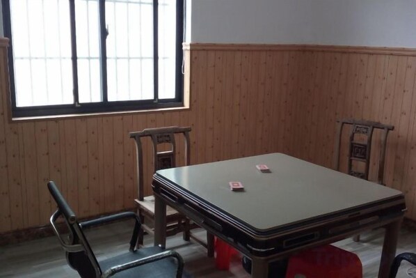 Una habitación con un revestimiento de madera, una mesa con sillas y una ventana con barrotes.