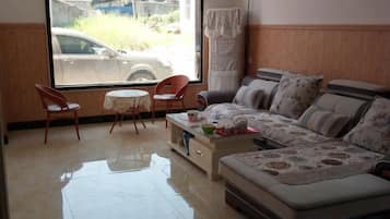 A living room with a sofa, two chairs, a coffee table, and a view of a car through a window.