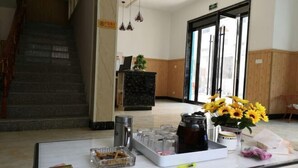 A reception area with a marble counter, a coffee machine, and a vase of sunflowers. - Loushanqiao Homestay No.2 (Shitai)