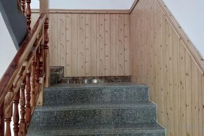 A wooden staircase with a handrail, leading to a landing with a metal bench. - Loushanqiao Homestay No.2 (Shitai)