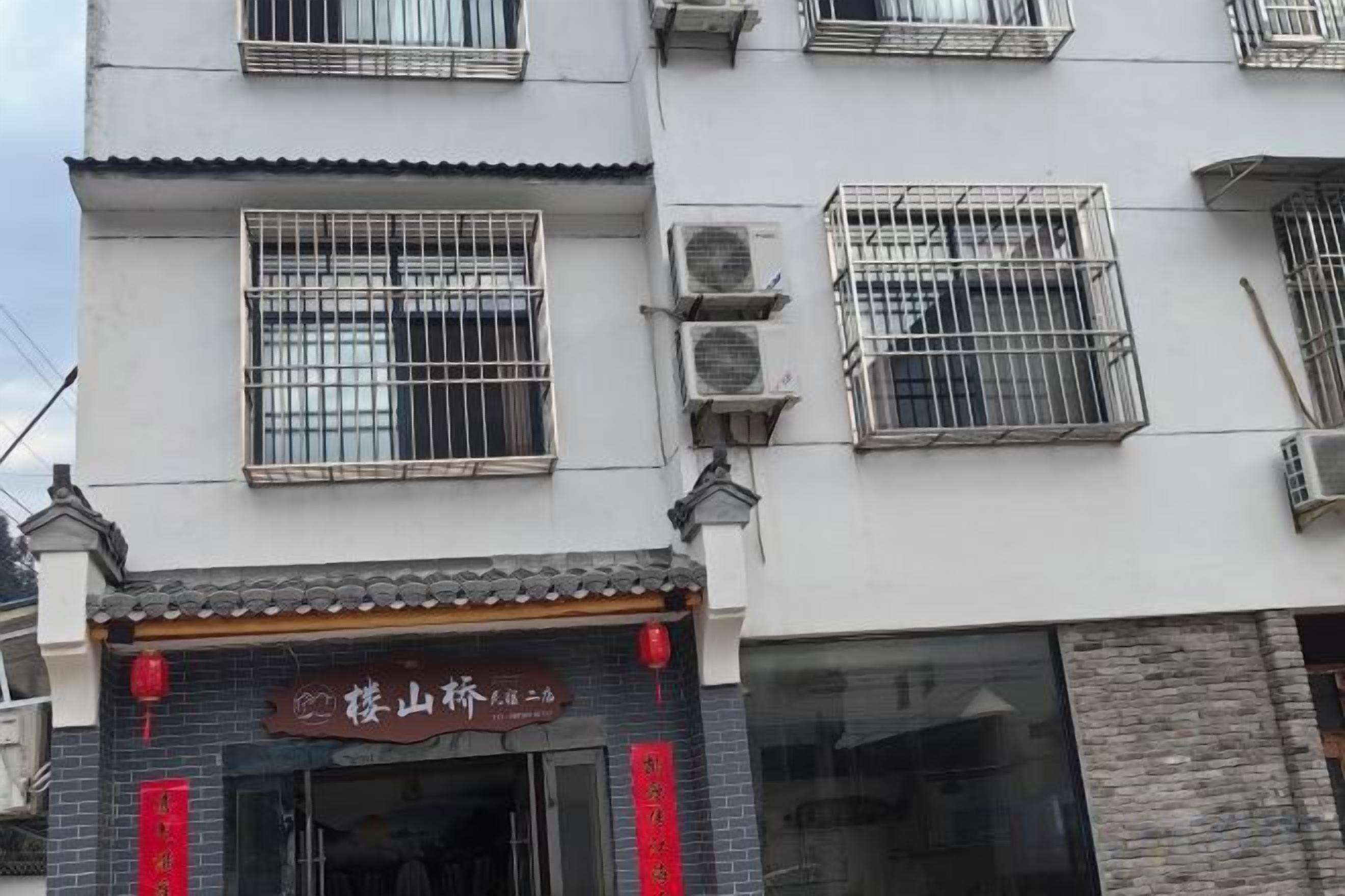A building with multiple windows, some with metal grilles, and a storefront with signage.