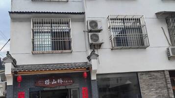A building with multiple windows, some with metal grilles, and a storefront with signage.