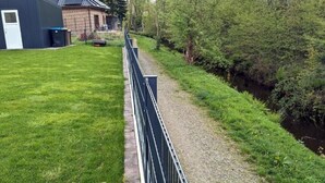 Une zone herbeuse avec un chemin de gravier et une clôture en métal.