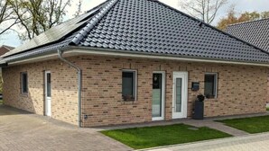 Un bâtiment d’un seul étage, construit en briques, avec un toit en pente, une porte d’entrée et un petit porche.