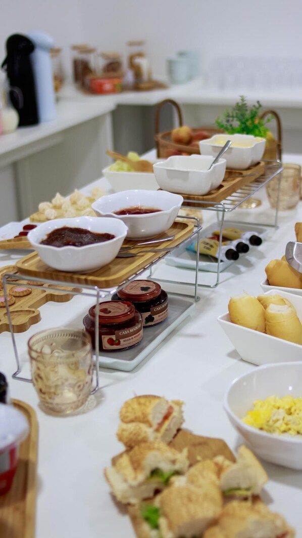 A buffet table with various food items and condiments. - Pousada Praia By Bia (Penha)