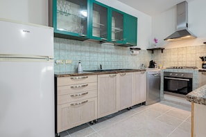 A kitchen with a white refrigerator, teal cabinets, a gas stove, and a dishwasher.