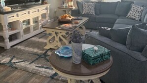 Un soggiorno con un divano grigio, un tavolino, una televisione e una lampada decorativa.