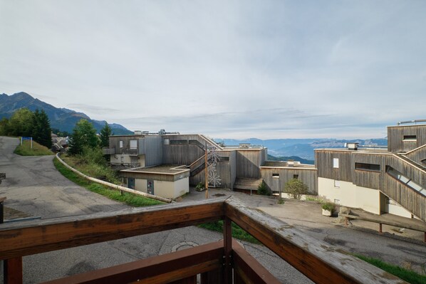 A modern building complex with multiple levels, wooden railings, and a view of distant mountains.