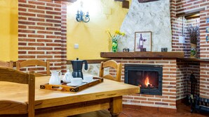 Zona pranzo con camino in mattoni, arredamento in legno e vassoio con accessori per il caffè.