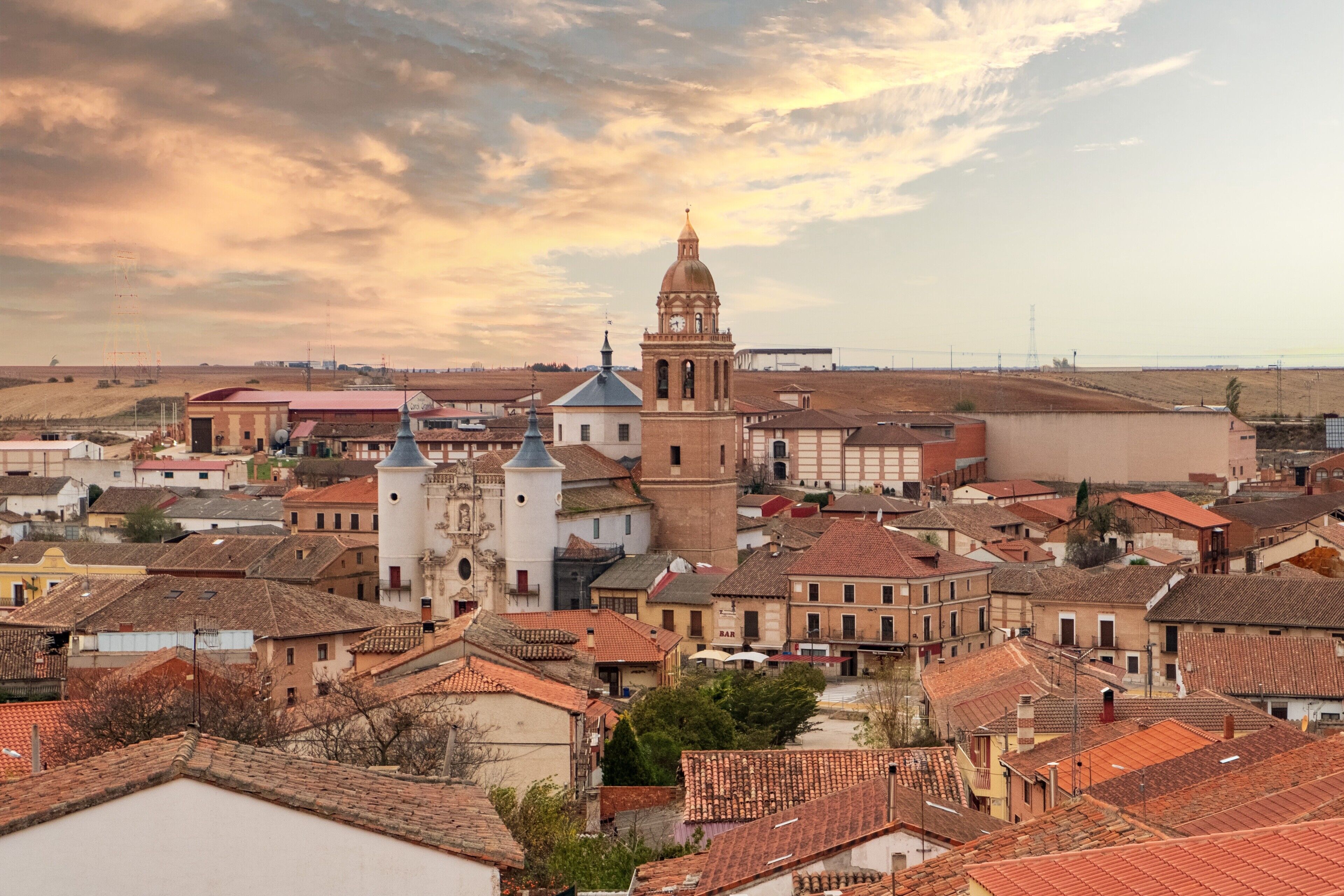 A town with historic buildings, a prominent church with a bell tower, and a clear sky.