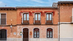 Un edificio in mattoni con tre finestre, ognuna con un balcone. Sopra le finestre è presente un cartello che recita 'Villa Calera Casa Rural'.