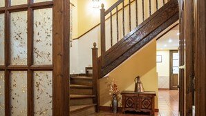 Una scala in legno con ringhiera, un vaso con fiori e un armadio.