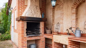 Forno in mattoni all'aperto con canna fumaria, lavello e secchio di metallo.