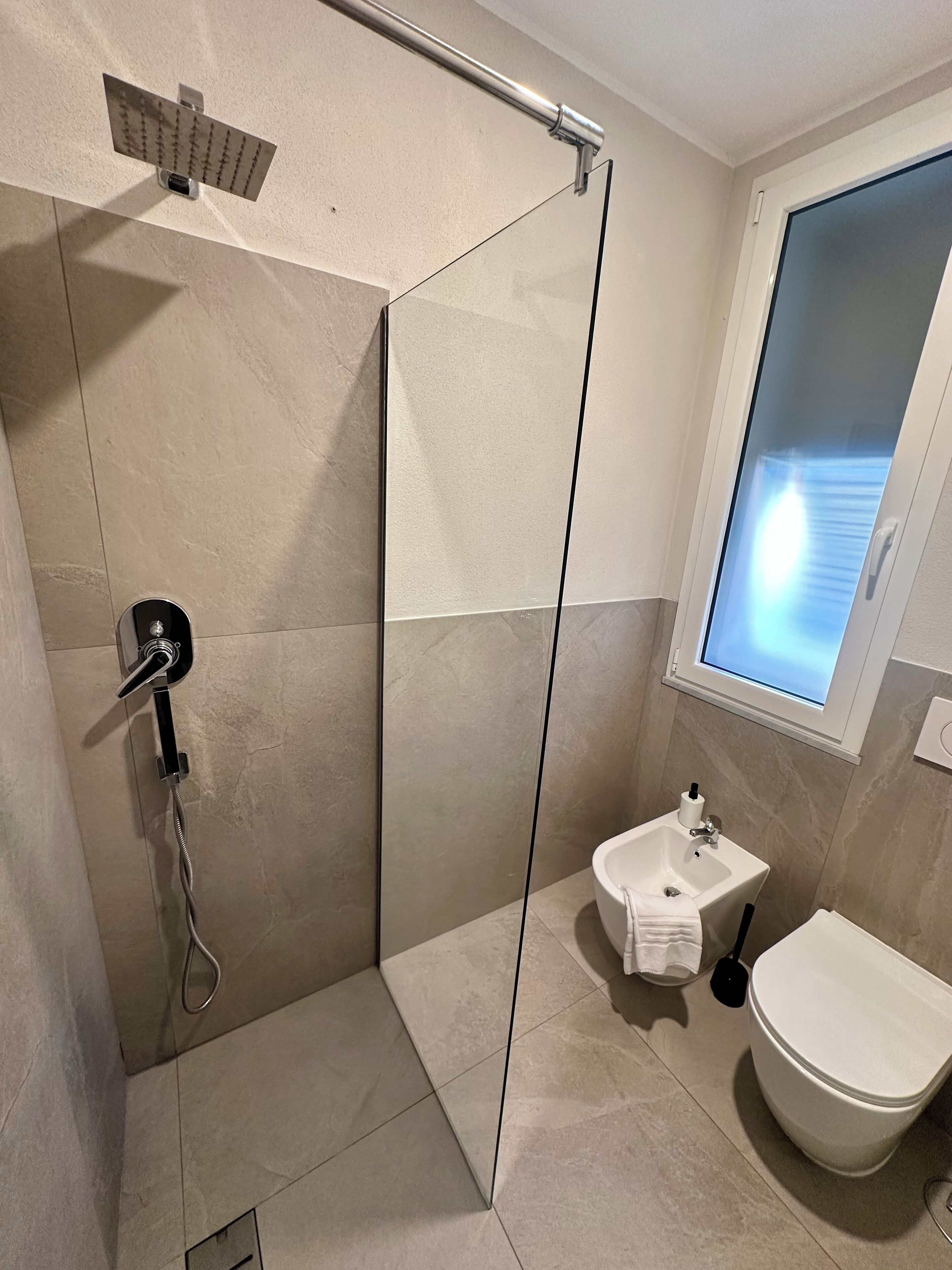 A modern bathroom with a glass-enclosed shower, a white sink, and a toilet.