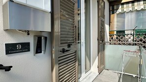 A modern building entrance with a metal gate, a sign indicating room number 9, and a small air conditioning unit mounted on the wall.