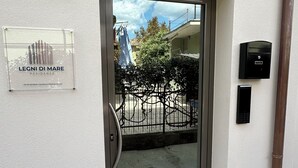 Entrada de um edifício residencial com porta de vidro, caixa de correio e câmera de segurança.