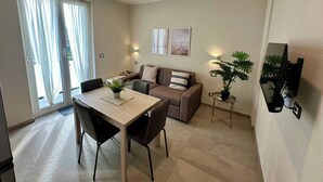 Una sala moderna con comedor, un sofá, una mesa de centro y una planta en maceta.