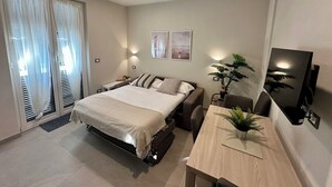 Un dormitorio moderno con cama, mesitas de noche, un escritorio y televisor.