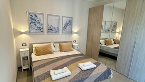 Une chambre moderne avec un grand lit, deux tables de chevet et un meuble-miroir.