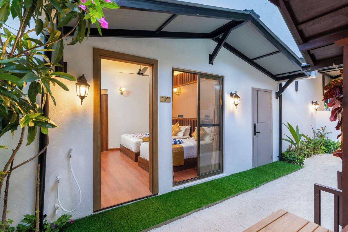 A modern hotel room with a sliding glass door, a bed, a shower, and a small balcony.
