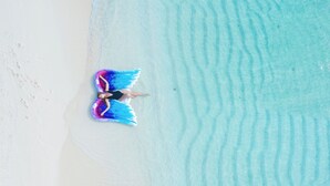 A person lying on a beach with a colorful wing-like object. - Ganduvaru Villa (Ukulhas)