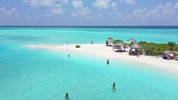 A beach with clear turquoise water, a sandy shore, and thatched-roof structures. - Ganduvaru Villa (Ukulhas)