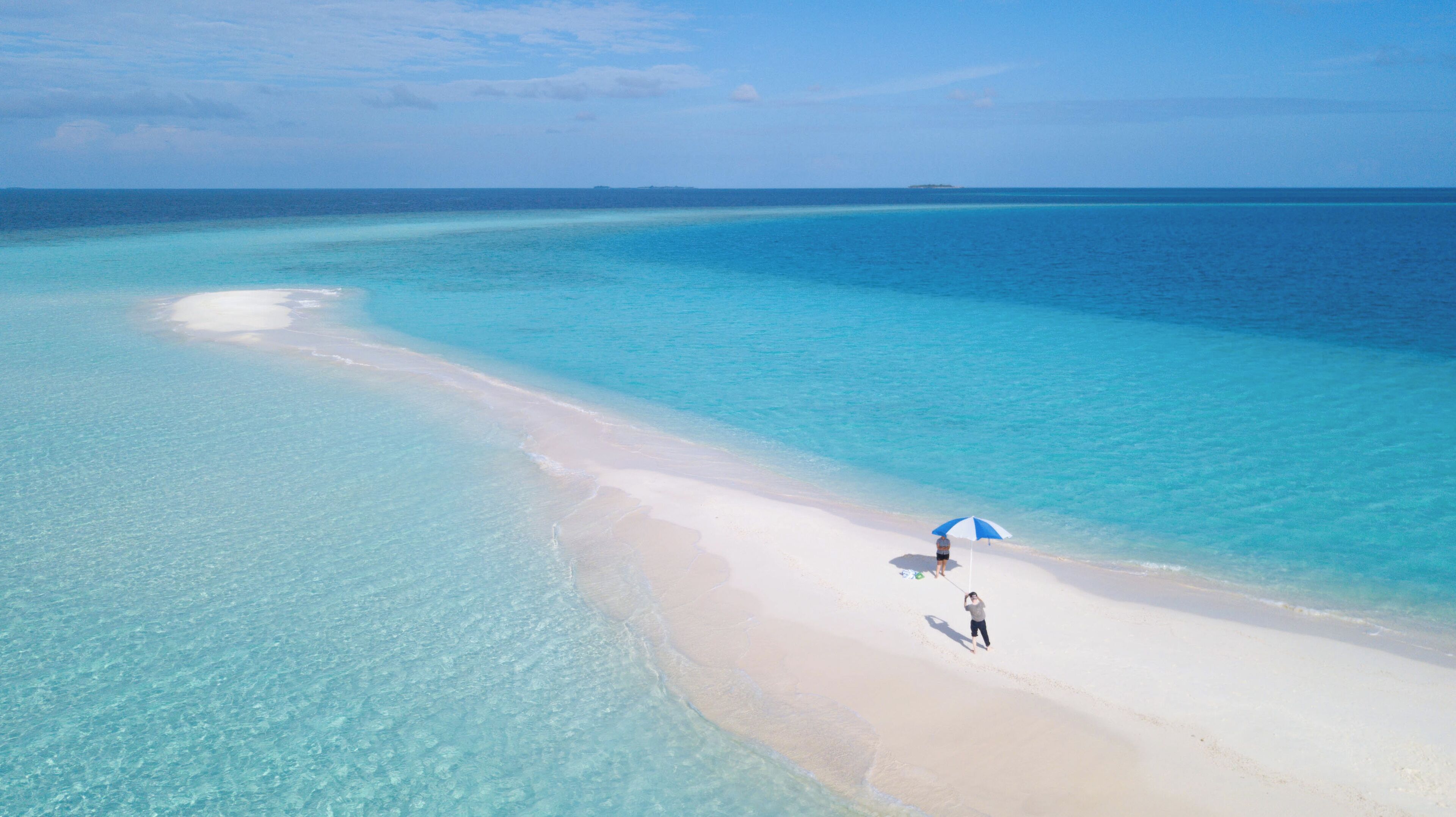 An aerial view of a beach with clear turquoise waters and a sandy shore.