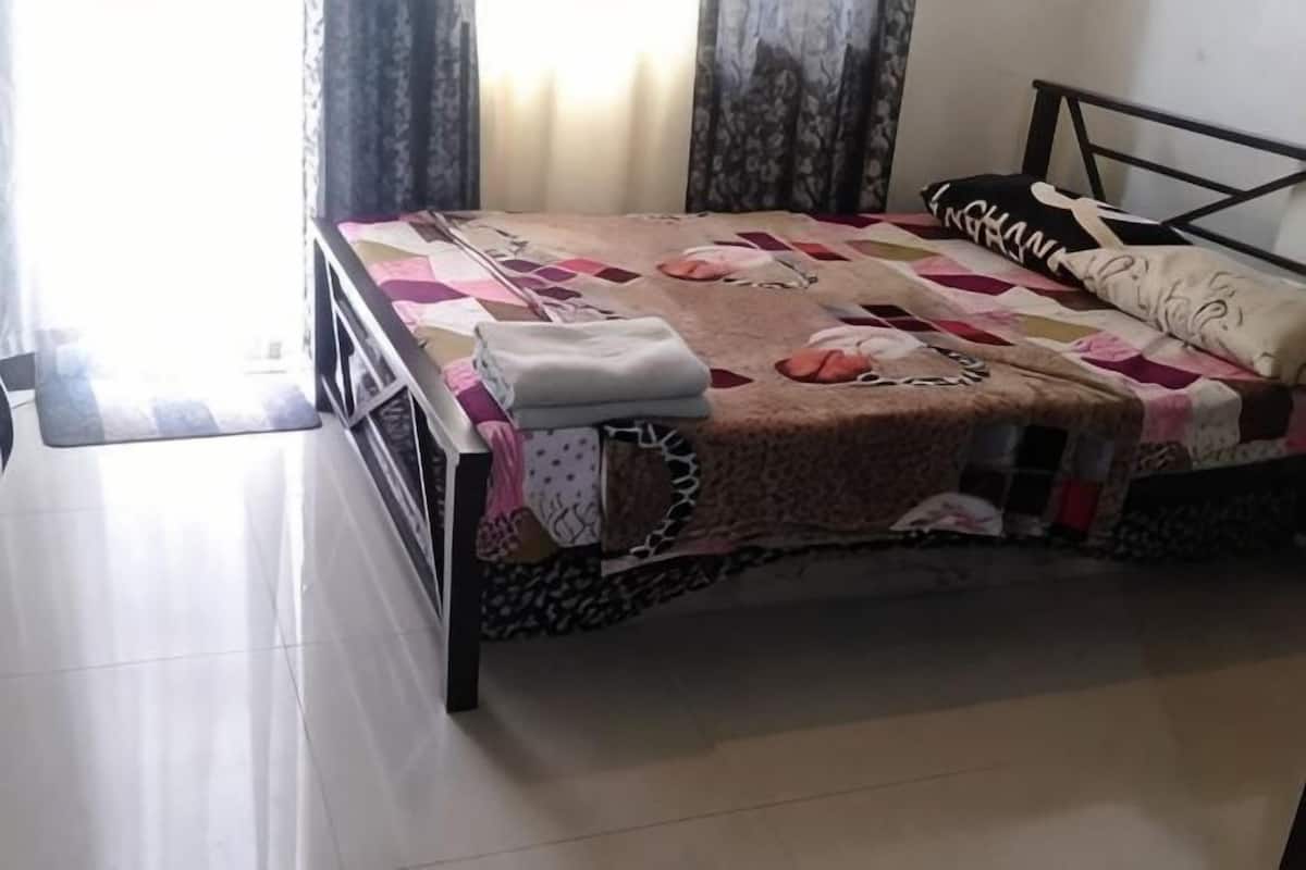 A bed with a patterned bedspread, a pillow, and a folded blanket on a metal frame.