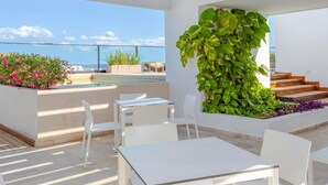 Terraza en la azotea con piscina, mobiliario blanco y jardín vertical.