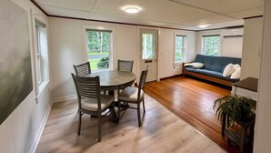 Et spiseområde med et rundt bord, fire stole, en sofa og en potteplante.